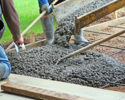 Crew placing and finishing fresh concrete during concrete slab preparation at a Langley construction site.
